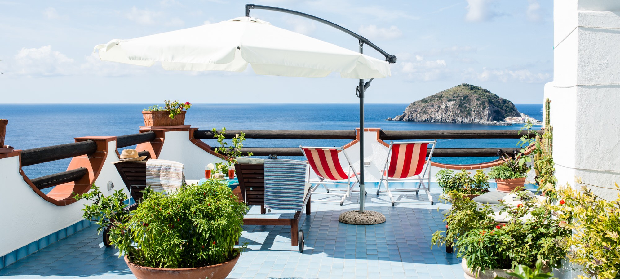 Terrazza con lettini solari e ombrellone ad Ischia con vista sul mare e sulla spiaggia