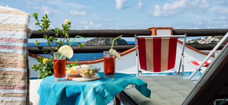 Terrazza con lettini solari e drink ad Ischia con vista sul mare e sulla spiaggia